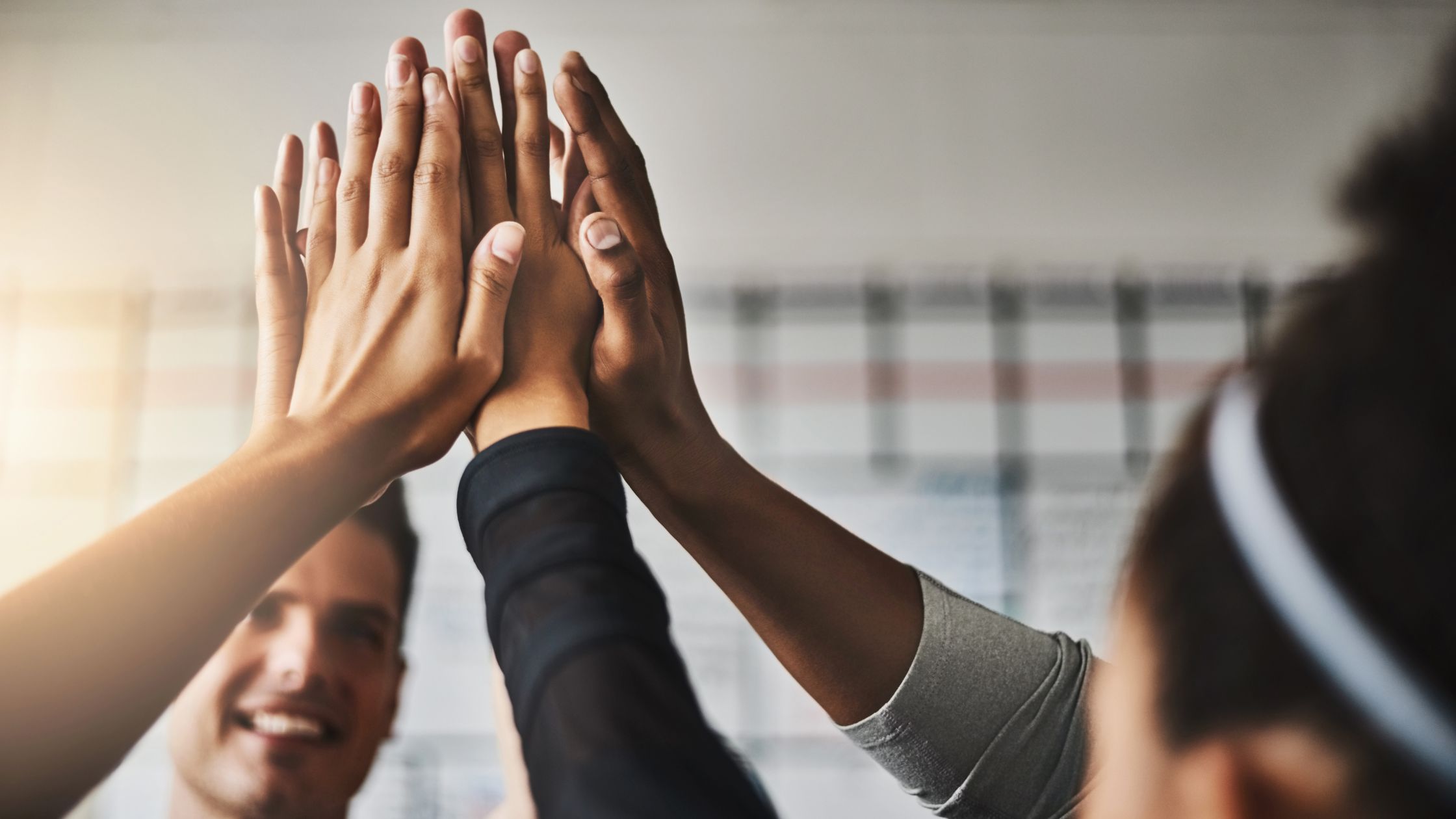 Teens giving a group high-five in a sports or fitness setting, fostering teamwork, motivation, and an active lifestyle.