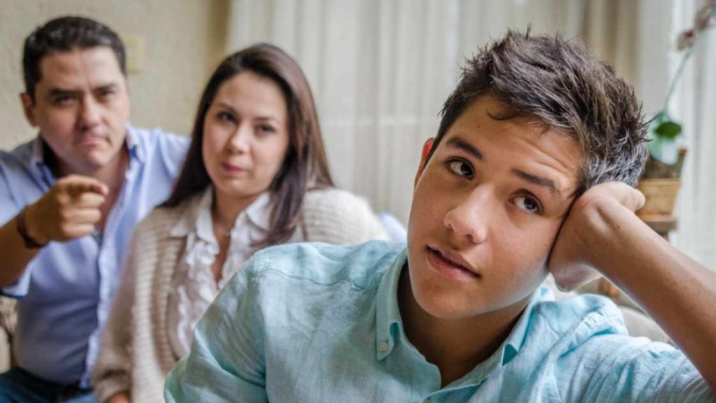 Frustrated teen ignoring parents during a conversation, illustrating challenges in choosing the right parenting approach.