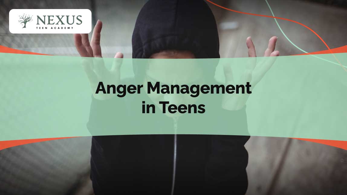 Teen in a dark hoodie with raised hands and tense posture, expressing frustration and anger.