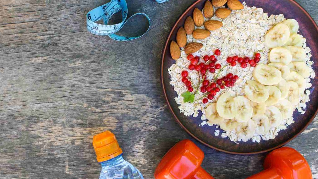 A healthy breakfast with oats, fruits, and nuts beside water and weights, highlighting teen nutrition's role in mental wellness.