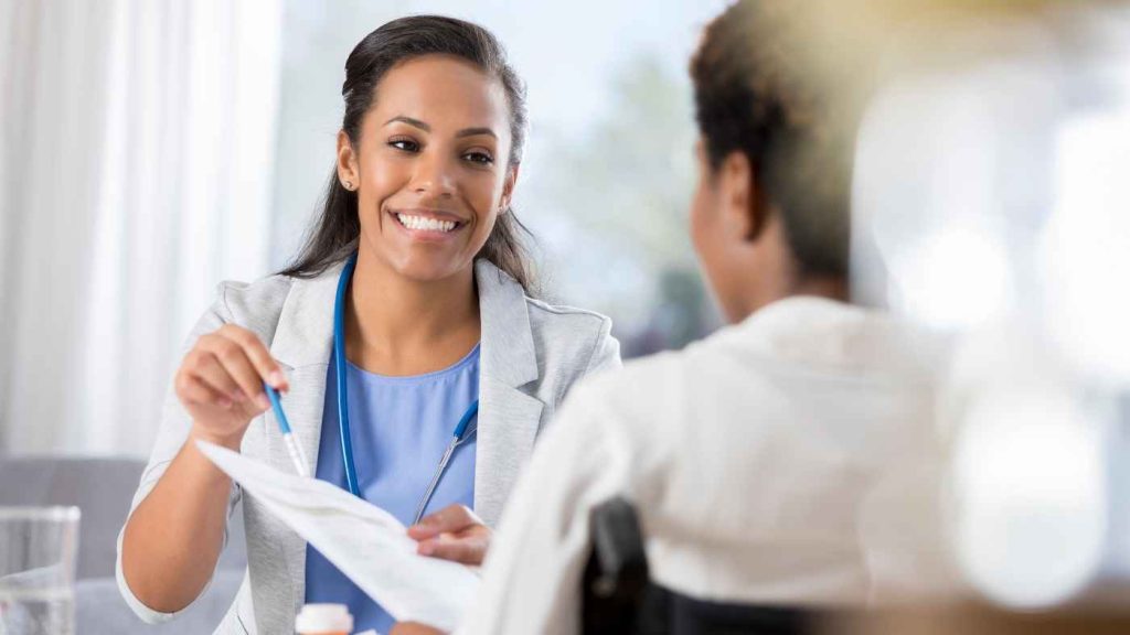 Healthcare provider smiles while reviewing discharge paperwork with teen patient, supporting transition from inpatient care to home.