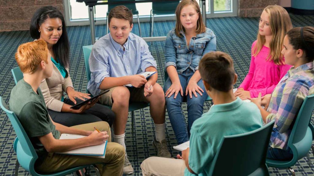 Group therapy session with teens and a counselor discussing mood disorders in an inpatient treatment program.