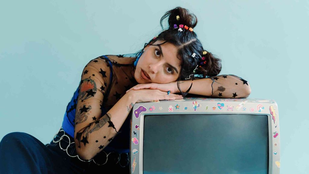 Teen girl with colorful hair clips leans on a sticker-covered TV, symbolizing distraction and possible ADHD signs.
