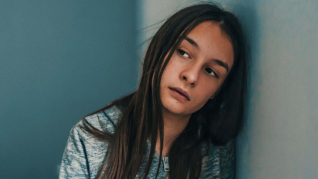 Sad teenage girl leaning against a wall, illustrating emotional struggle in “What Teen Depression Looks Like.”