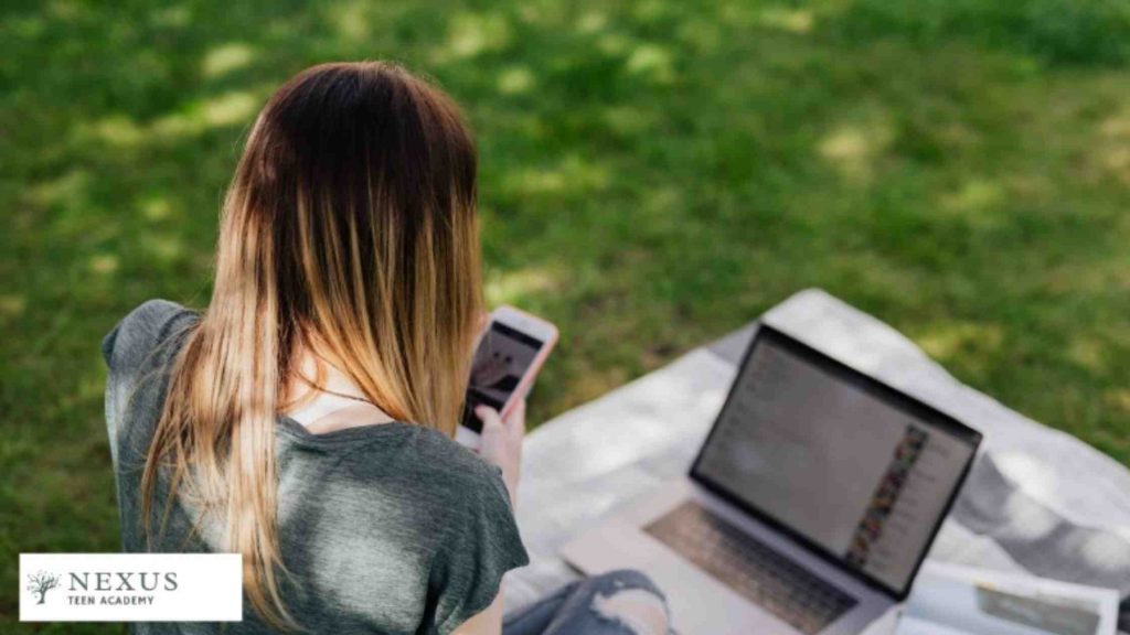 Teen girl using smartphone and laptop alone, representing parental guidance and digital supervision to prevent cyberbullying.