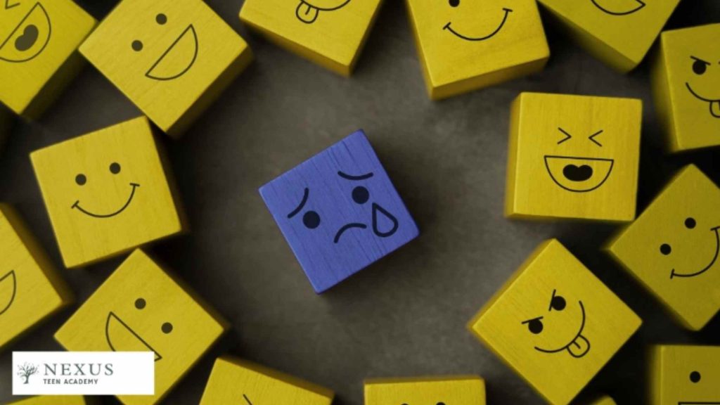 A blue sad face block surrounded by yellow happy faces, representing bullying, isolation, and emotional distress.