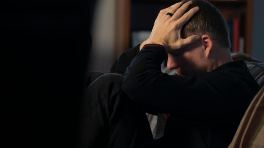 A worried parent sitting with his head in his hands, reflecting the emotional impact after knowing their teen uses marijuana.