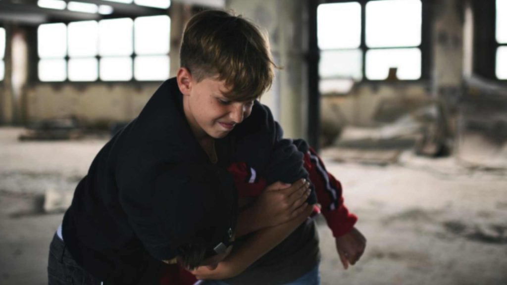 Two teenage boys fighting in an abandoned building, illustrating aggression linked to causes of conduct disorder in teens.