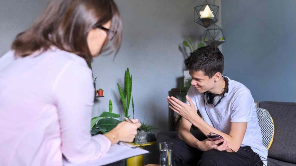 Teen boy speaks with a therapist in residential treatment session, reflecting emotional support and daily guidance.