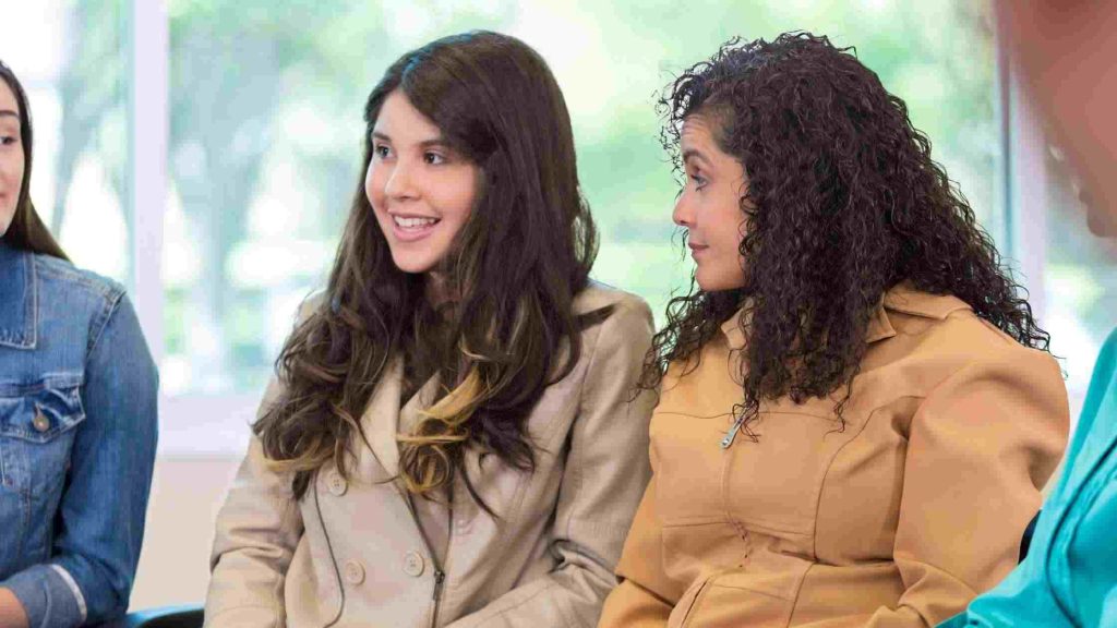 Teens-therapist sit together in a group setting, reflecting evidence-based trauma therapies like CBT, EMDR, & group healing.