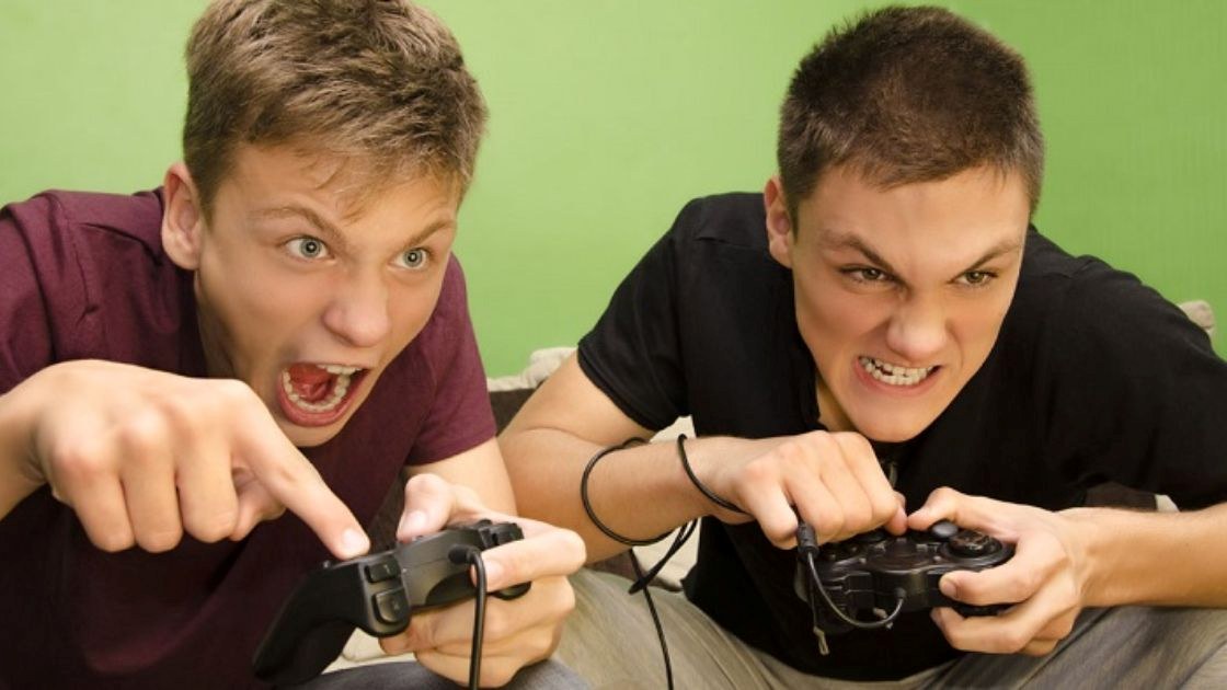 Teen boys shouting in frustration while playing video games, showing how competitive losses can trigger anger.
