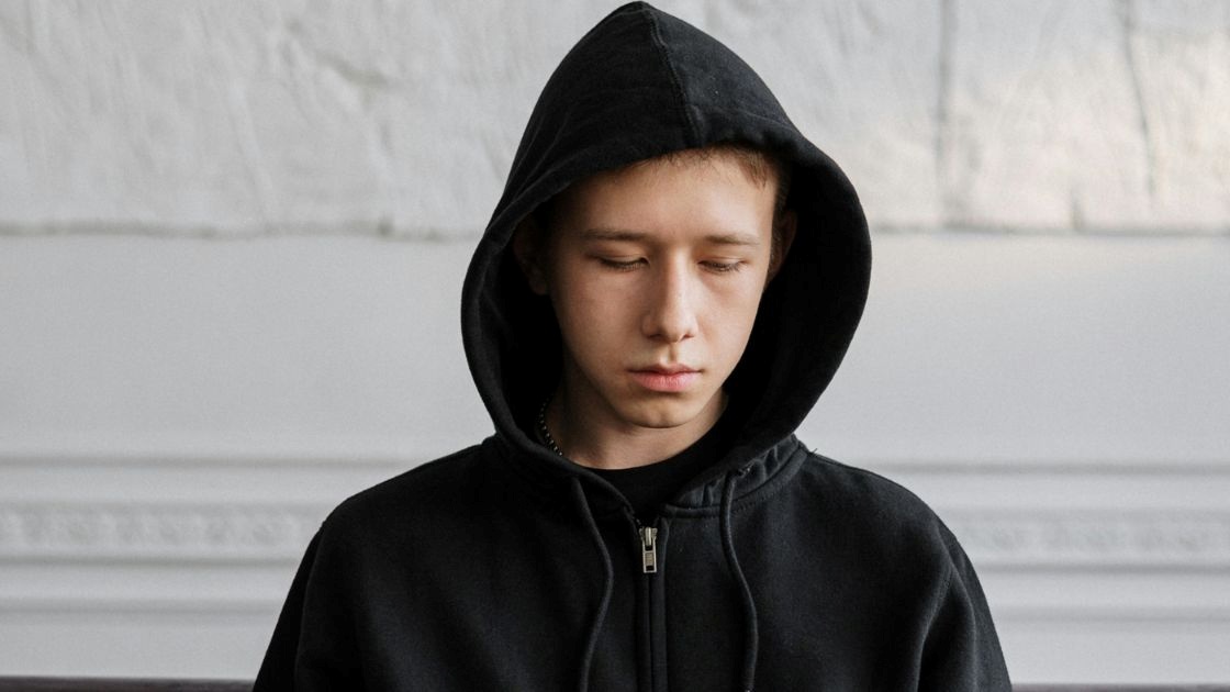 Teen boy in hoodie looking withdrawn and fatigued, reflecting early warning signs parents should recognize.
