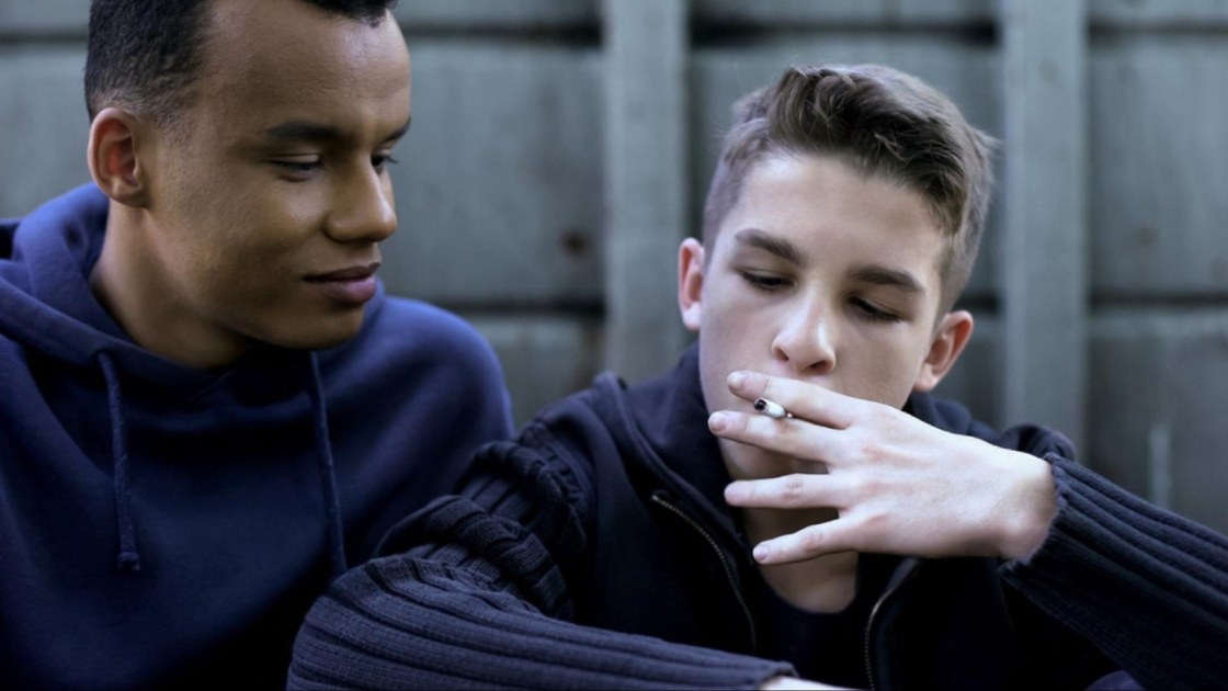Teen smoking marijuana with a friend, showing how peer influence and environment can normalize risky behavior.
