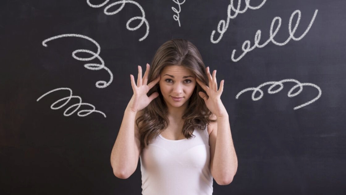Teen girl holding her temples as swirling thoughts illustrate stress overload and emotional strain on the adolescent brain.