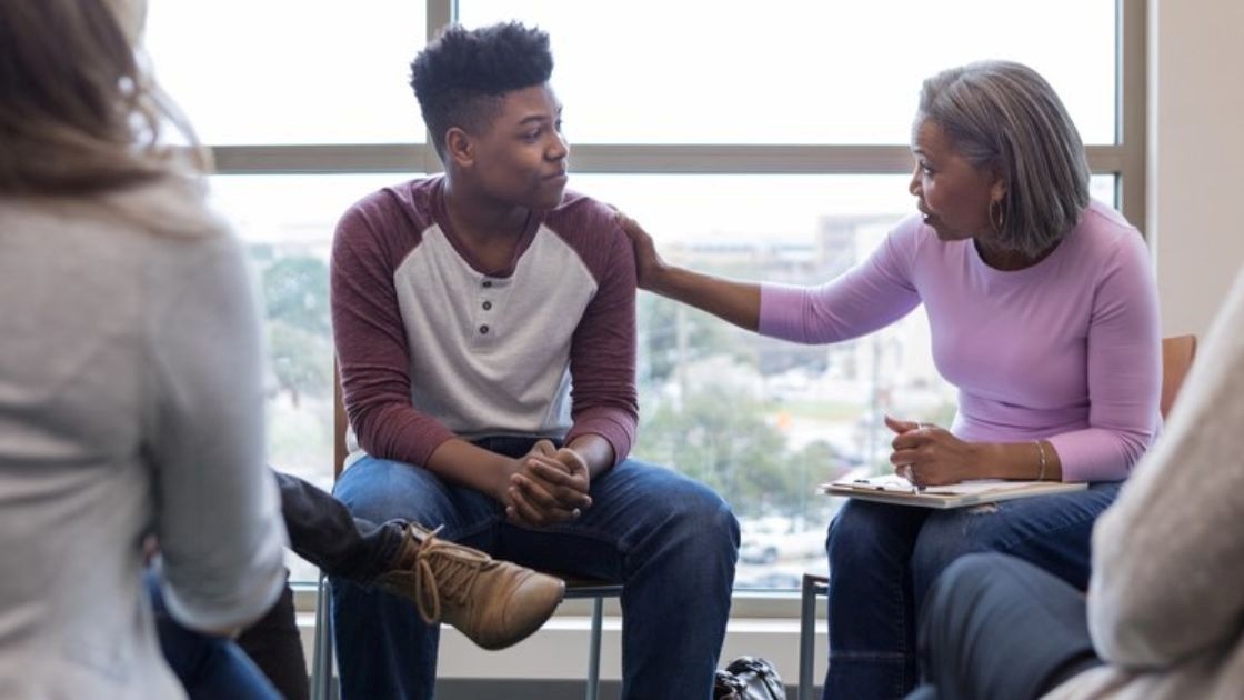 Parent and teen in supportive therapy session discussing feelings and building trust through guided conversation.