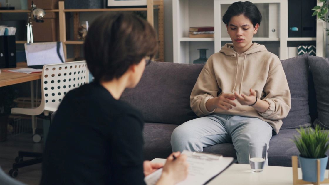 Teen boy speaking with therapist during session, representing treatment options for panic attacks in teens.