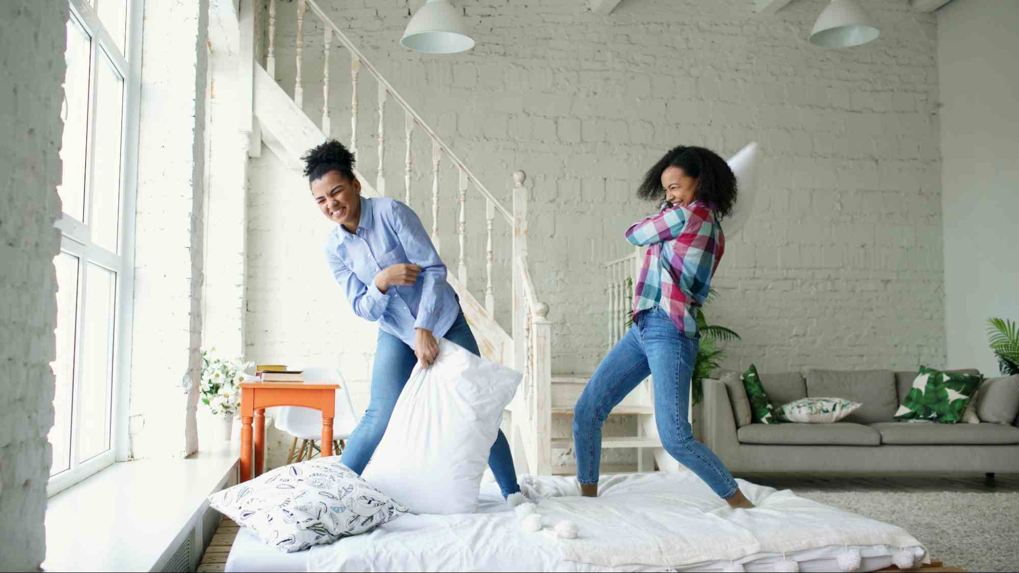 Two siblings laughing during a pillow fight, symbolizing renewed family bonds and healthy sibling connection after conflict.