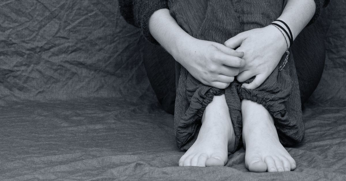 Teenage boy sitting alone, withdrawn after years of bullying