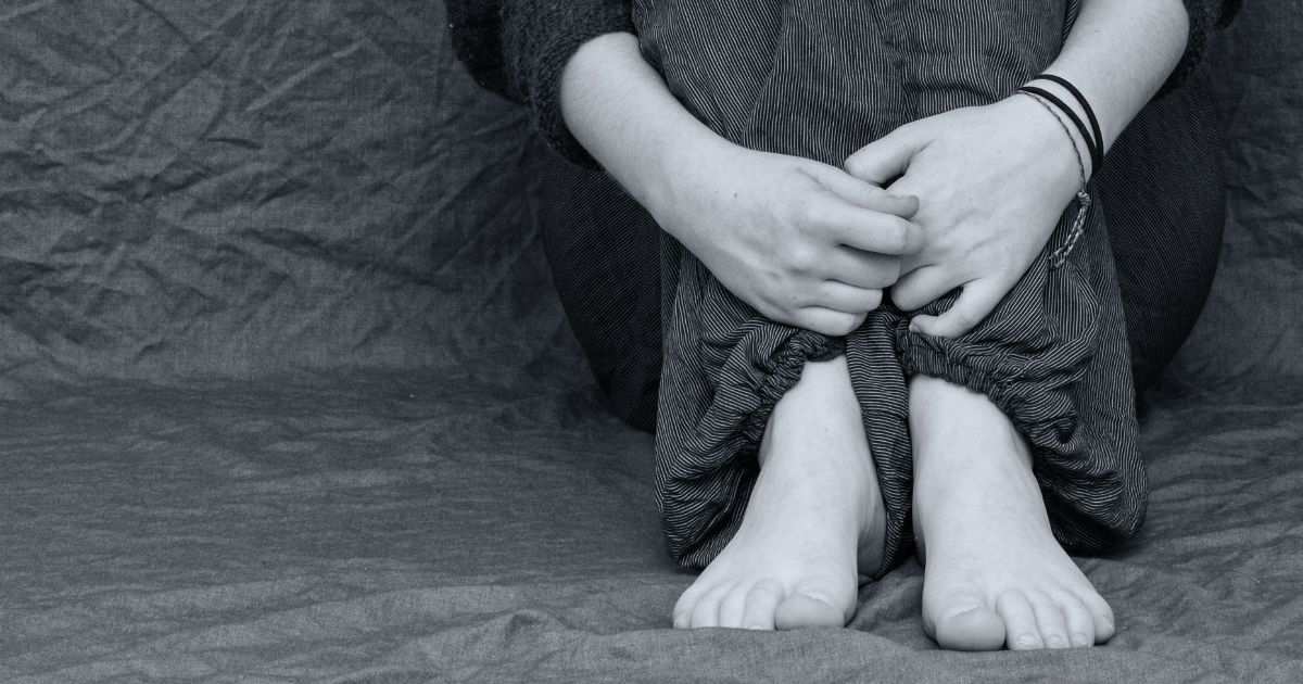 Teenage boy sitting alone, withdrawn after years of bullying